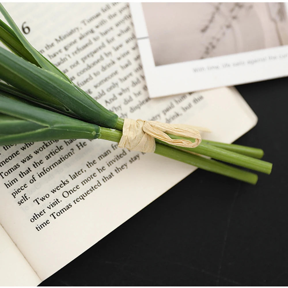 Artificial dandelion bouquet with vibrant green stems arranged on a book and vintage photos