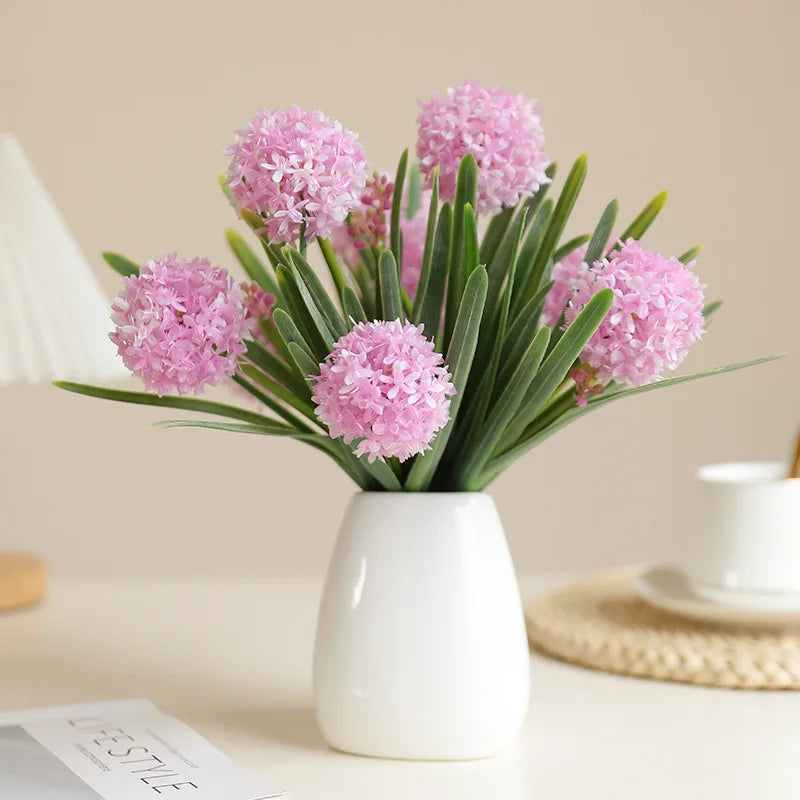 Artificial dandelion bouquet in a white vase with pink dandelions and green leaves, perfect for home decor