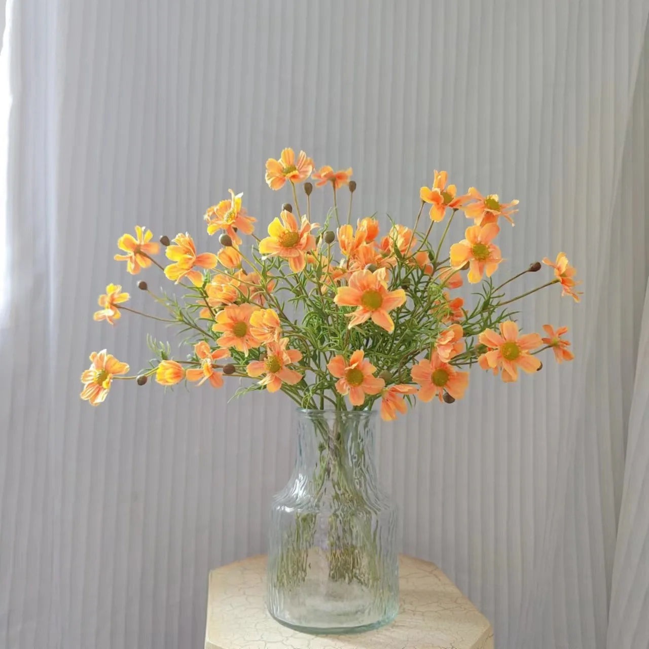 Bright orange artificial flowers in a glass vase for home decor and arrangements