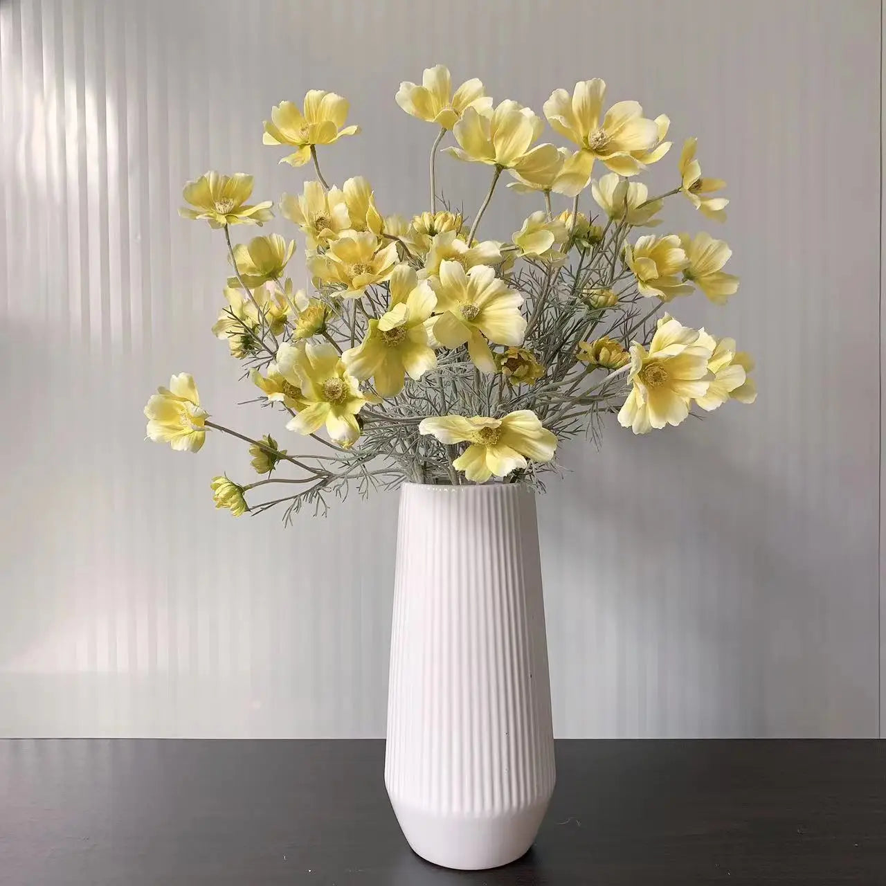 Elegant white vase with yellow flowers and delicate greenery for home decor