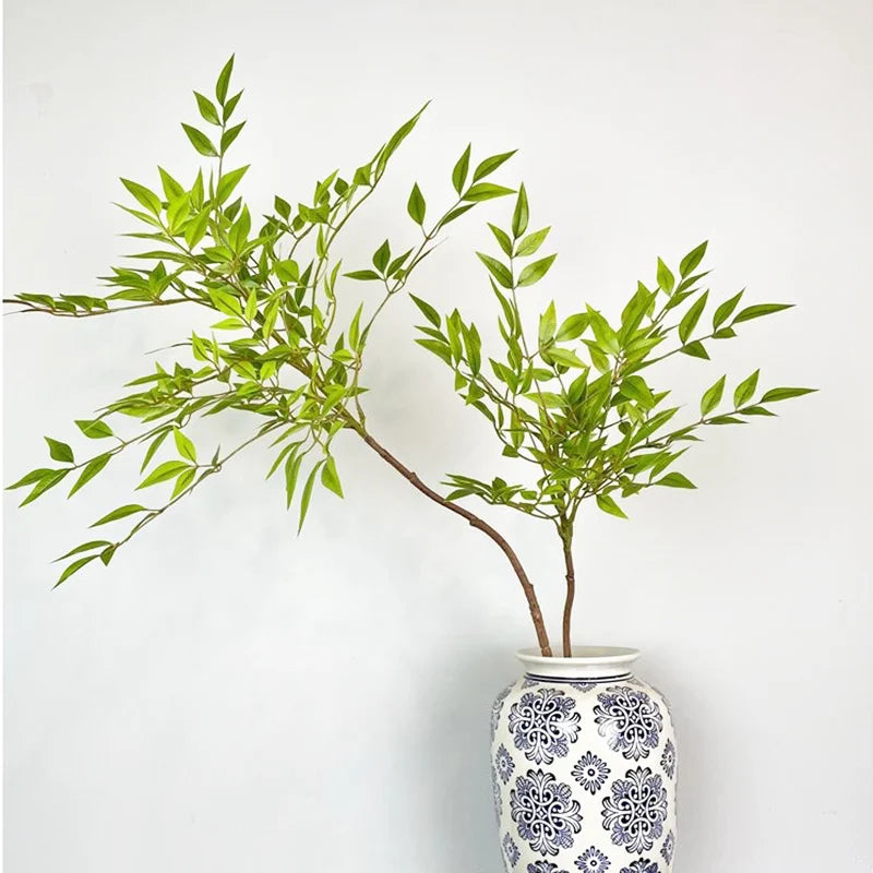 Artificial green leafy branch in a blue and white decorative vase for home decor
