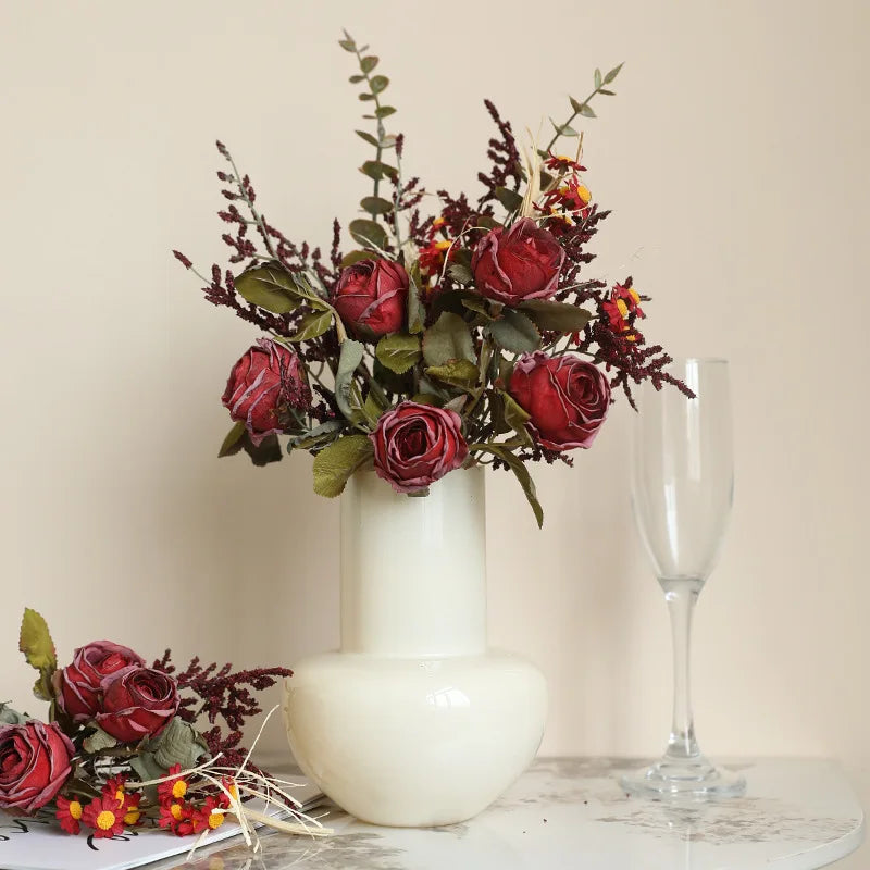 Artificial rose bouquet autumn in a white vase with decor leaves and dried flowers