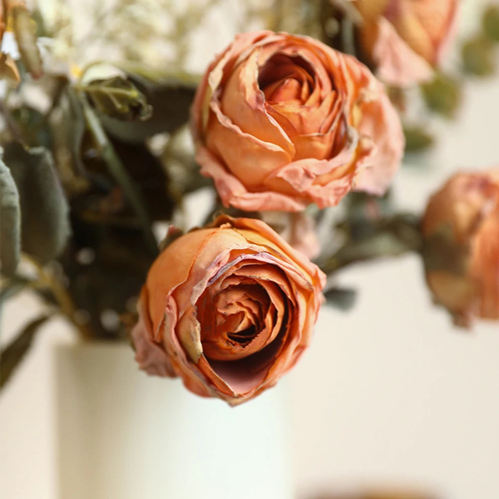 Artificial rose bouquet autumn featuring soft orange roses and green foliage in a decorative vase