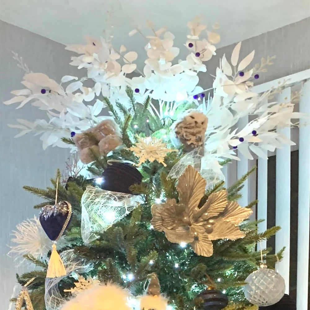 Artificial white flower decoration atop a beautifully lit Christmas tree with gold and blue ornaments