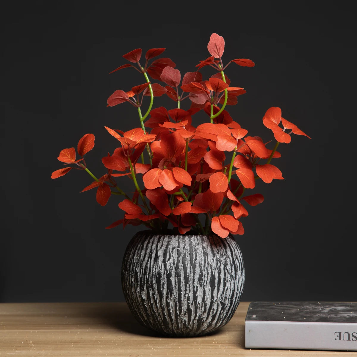 Artificial red leaf plant in a textured black vase for home decor and interior styling