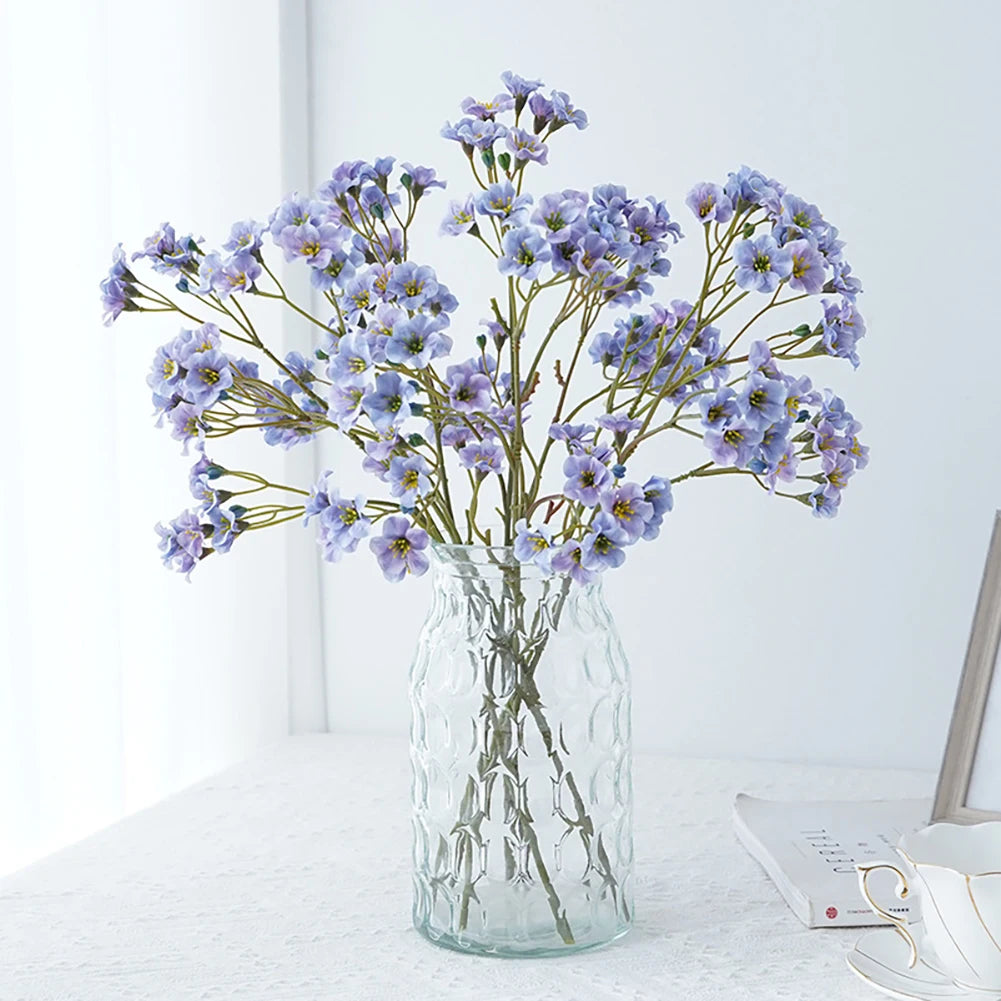 Beautiful purple fake flower table decorations in a transparent glass vase for home decor