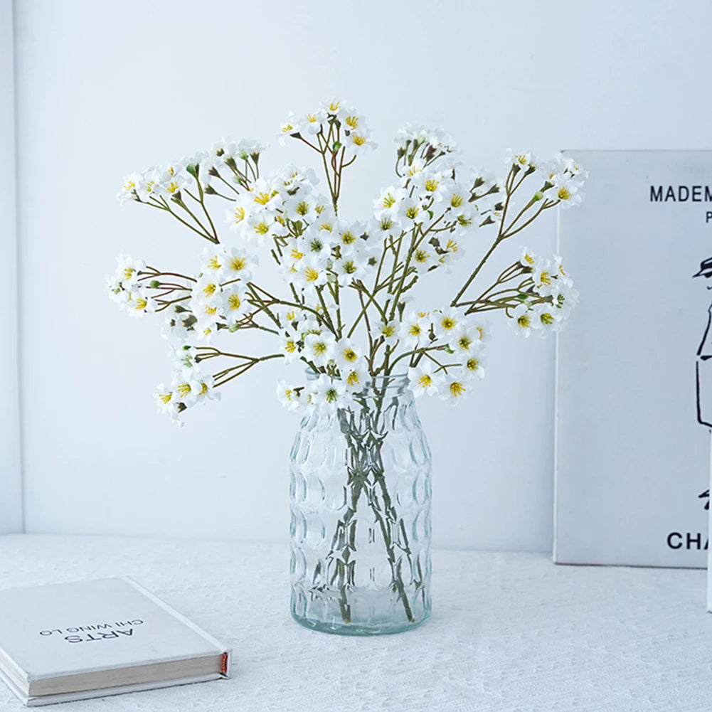 Elegant fake flower table decorations in a clear vase, perfect for home or event styling.