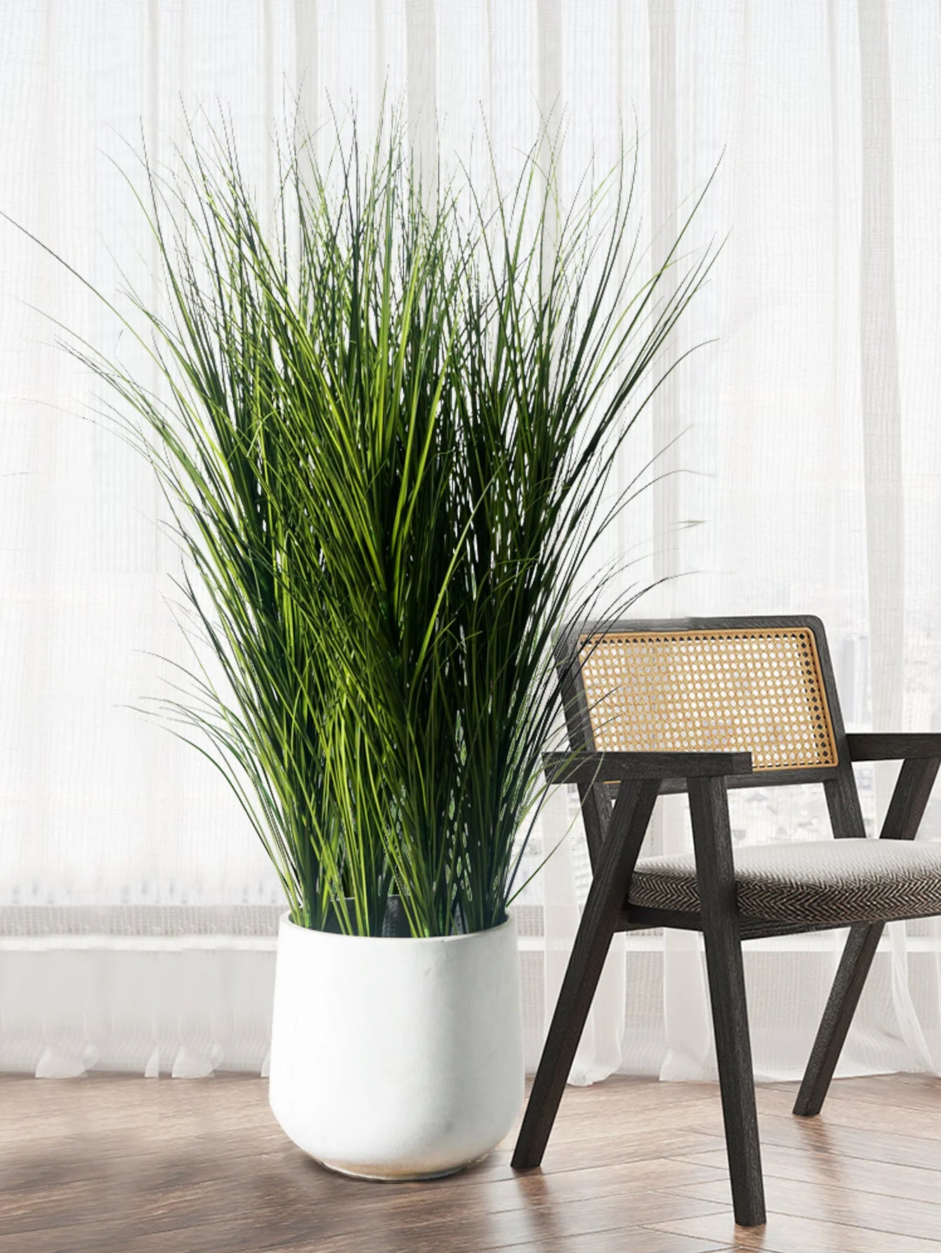 Tall decorative fake grass plants for office in a white pot beside a modern chair