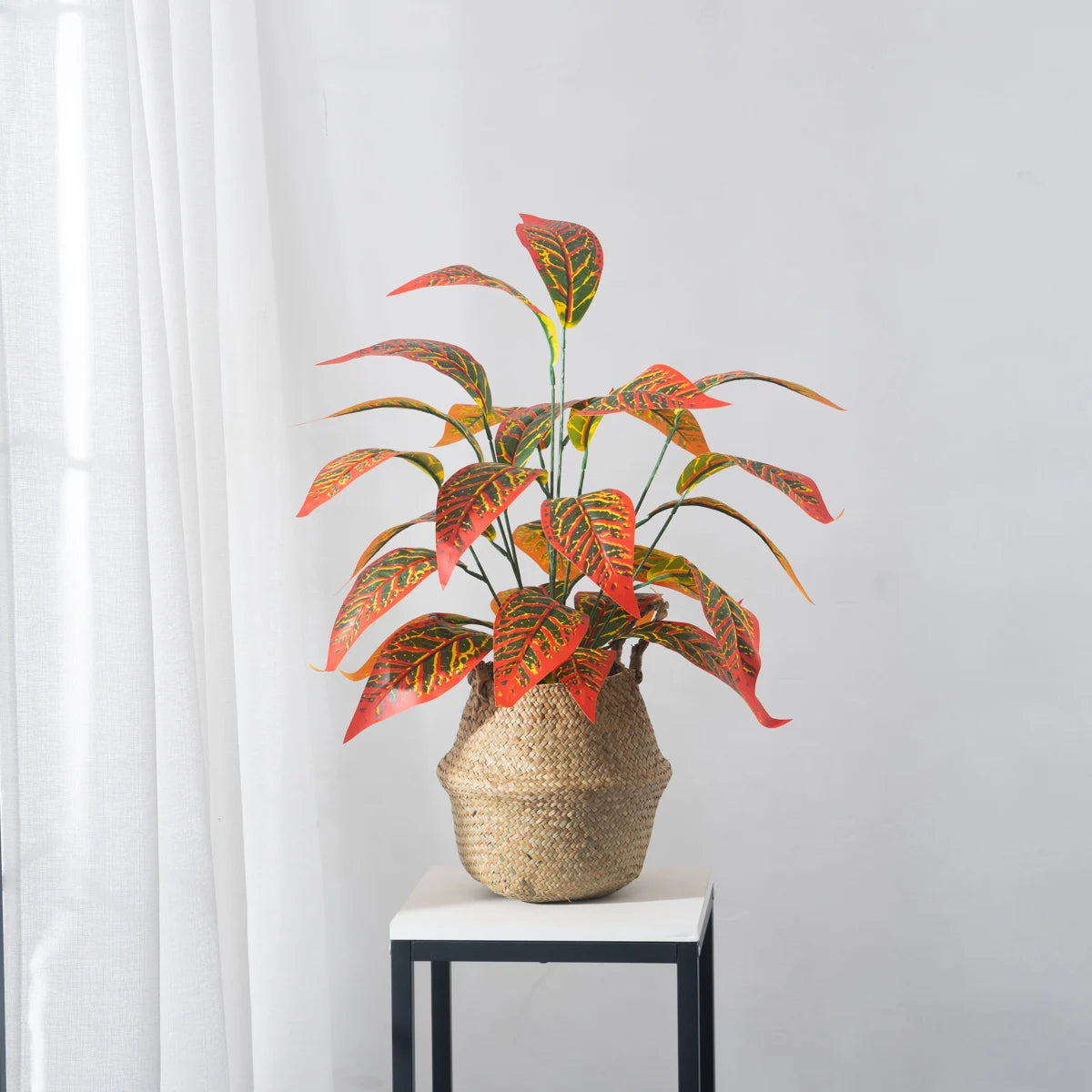 Colorful potted fake magnolia branch decor with vibrant leaves in a stylish woven basket