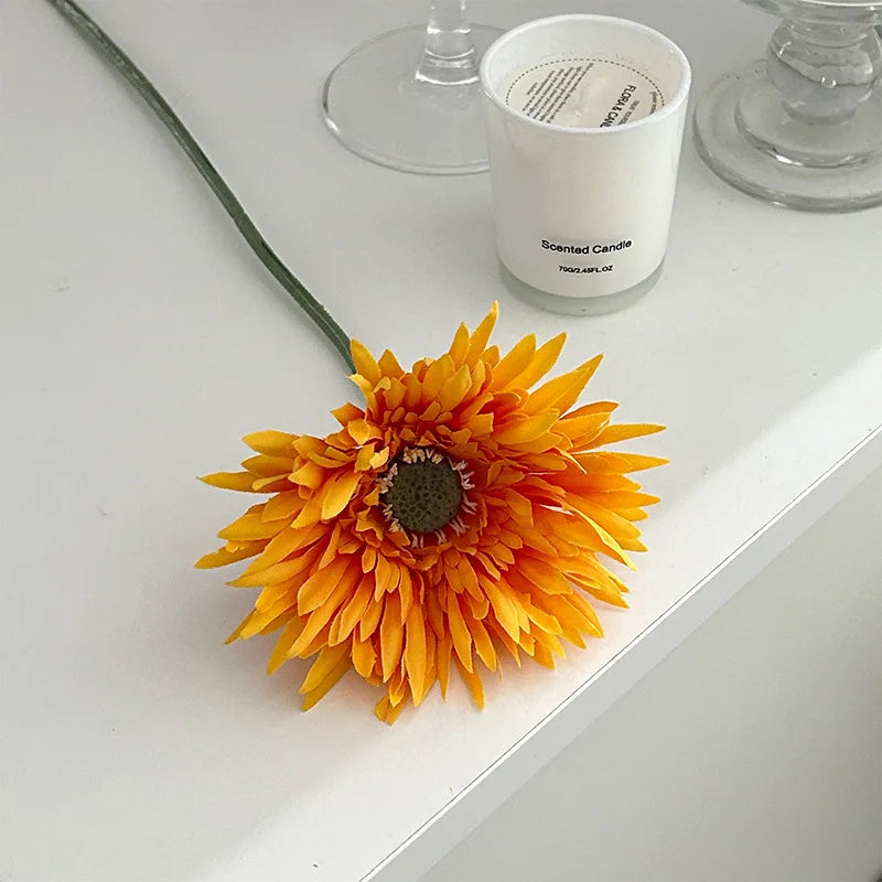 Bright orange Gerbera artificial flower 2025 placed near a scented candle for home decor