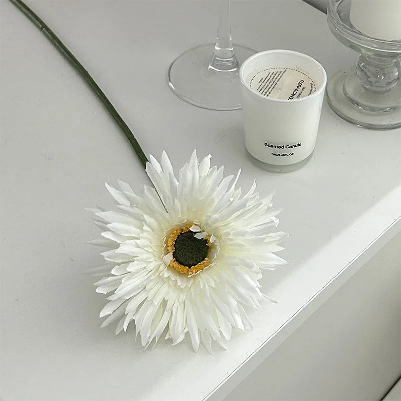 White Gerbera artificial flower 2025 placed on a table next to a scented candle for home decor