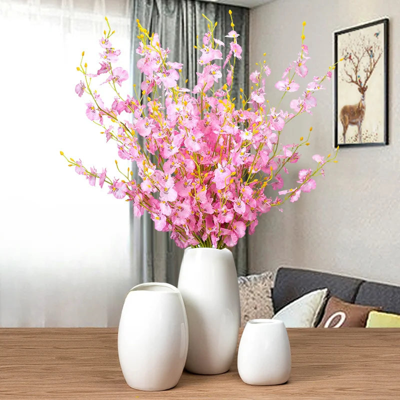 Set of white ceramic vases with pink artificial flowers for home decor and elegant interior styling
