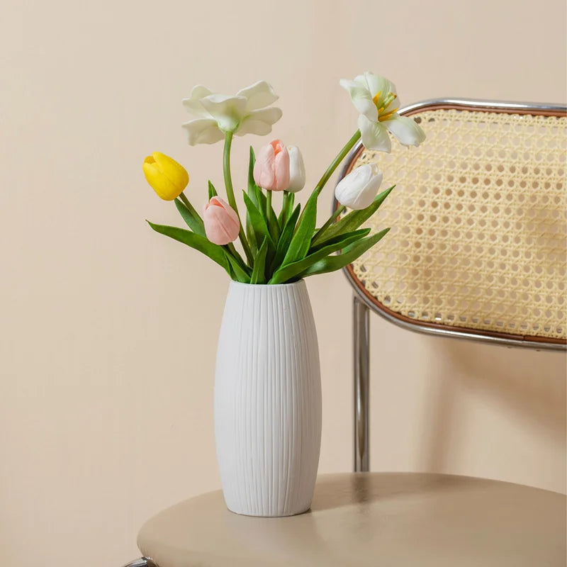 Elegant white ceramic jarrones for home decoration with colorful artificial flowers arranged inside