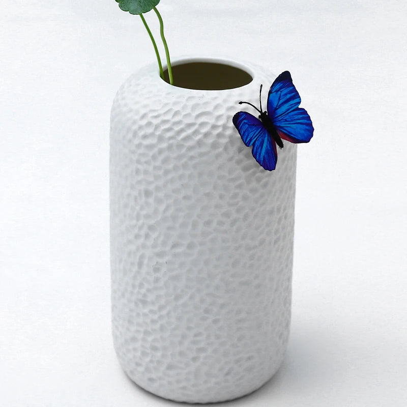 White modern ikebana vase with textured surface and a decorative blue butterfly accent