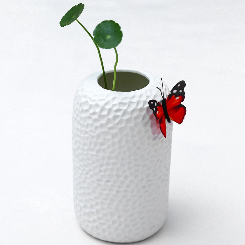 White modern ikebana vase with a textured surface and decorative butterfly and green stems