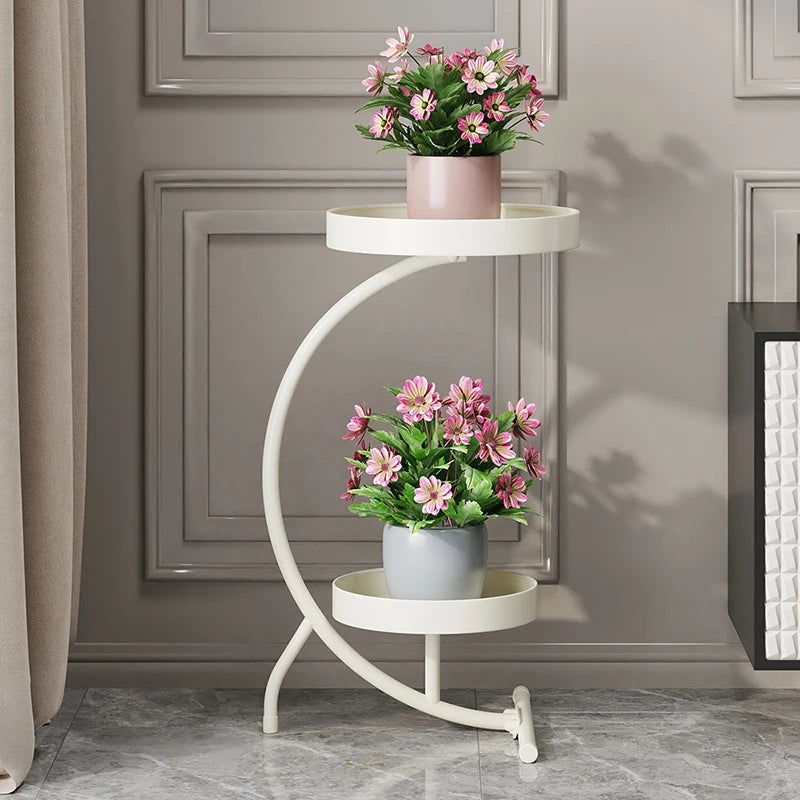 Modern plant stand indoor with two circular tiers displaying potted pink blooming flowers