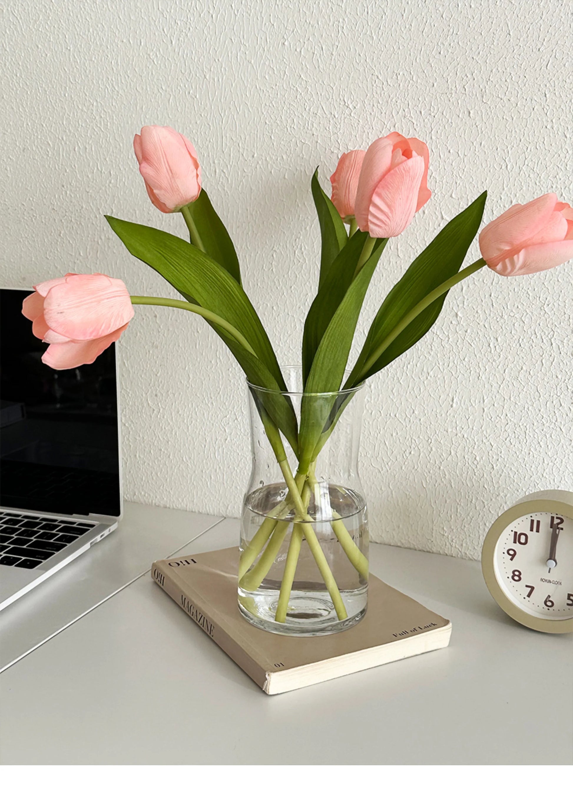 Nordic glass vase decor featuring pink tulips on a desk with a clock and laptop