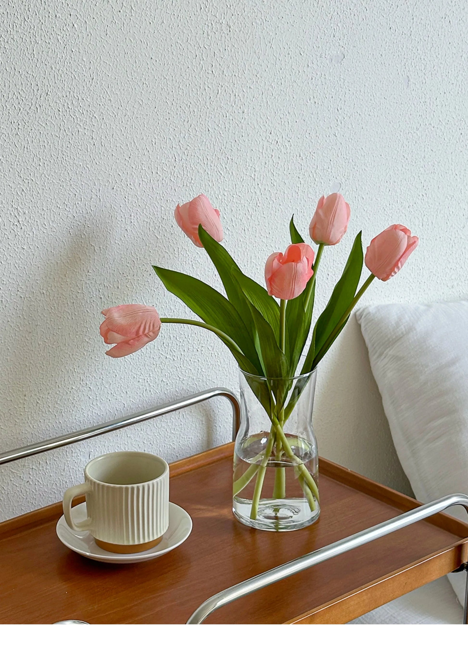 Nordic glass vase decor featuring pink tulips on a wooden tray with a cup and saucer