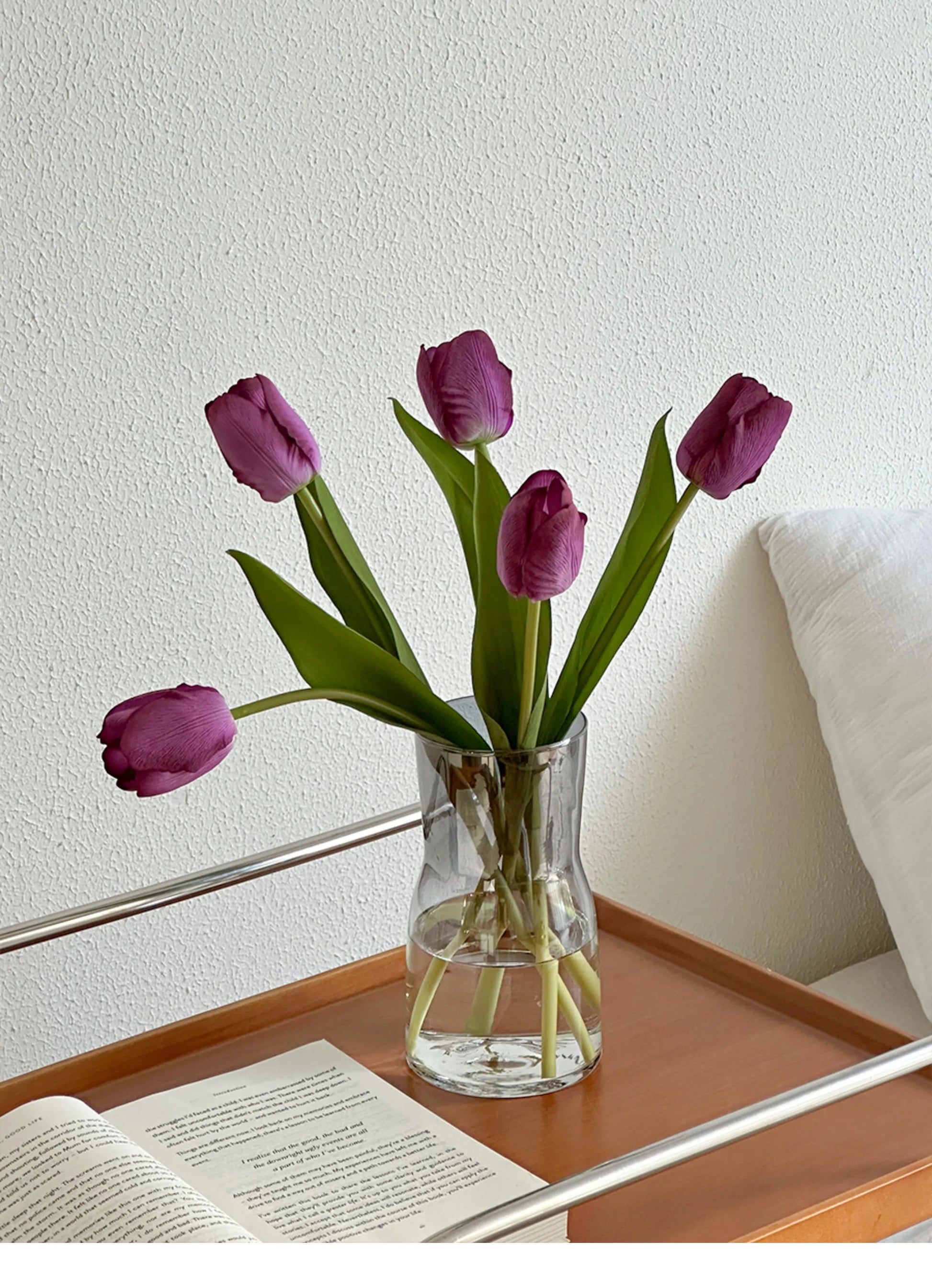 Nordic glass vase decor with purple tulips and green leaves on a wooden table