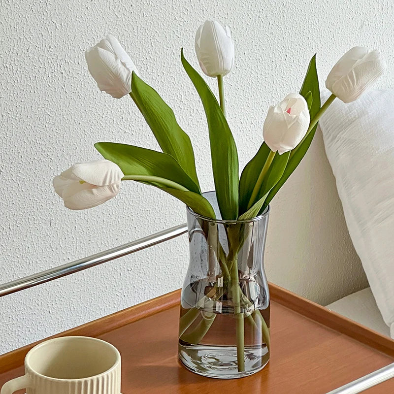Nordic glass vase decor filled with white tulips on a wooden tray beside a cup
