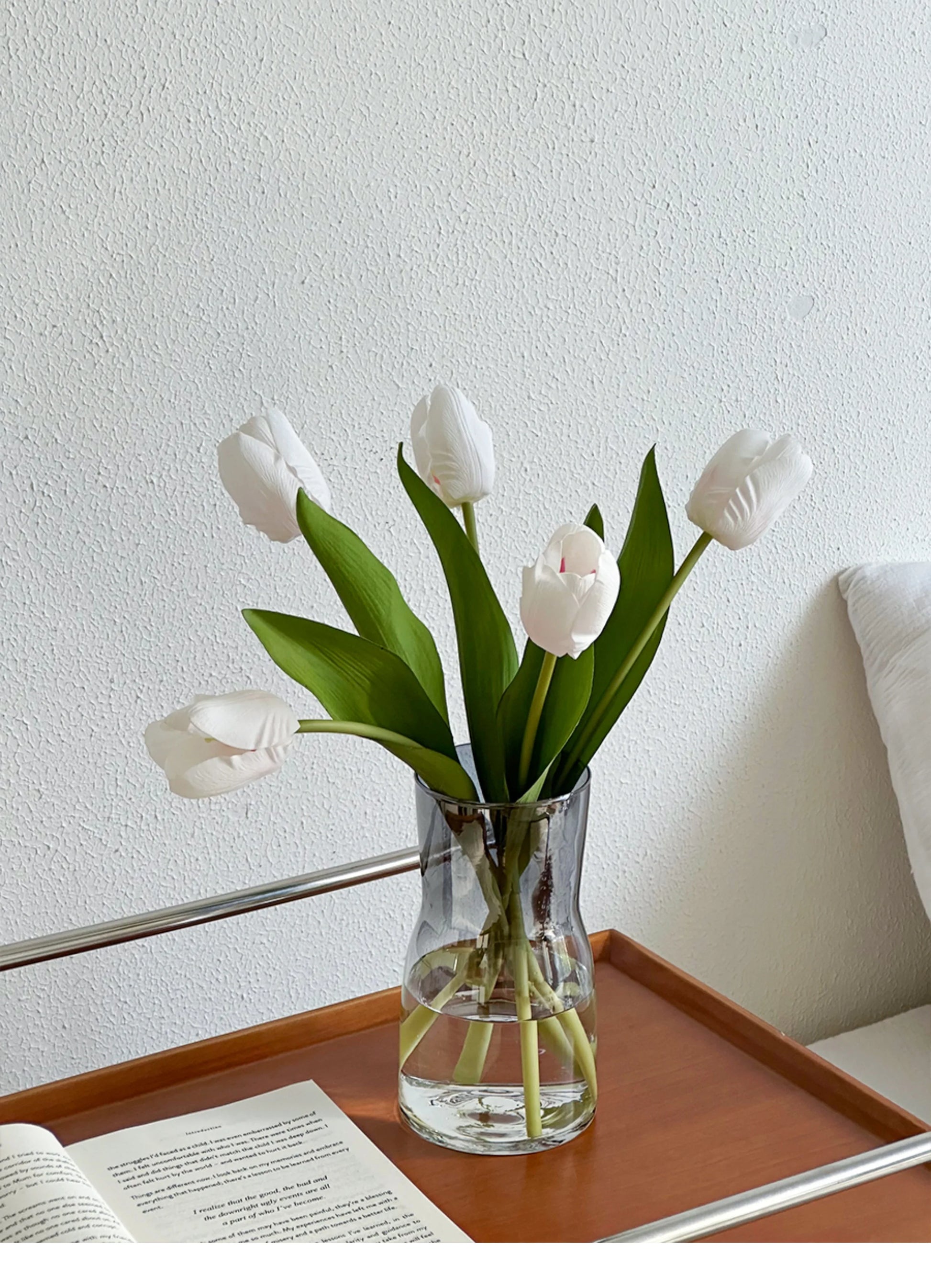 Nordic glass vase decor featuring white tulips and green leaves on a wooden tray