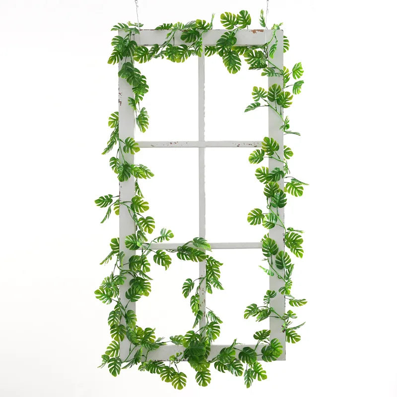Plastic turtle leaf garland draping elegantly from a vintage window frame with vibrant green leaves