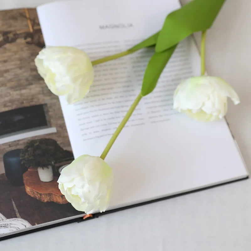 White artificial tulips beautifully arranged on a coffee table book for home decor