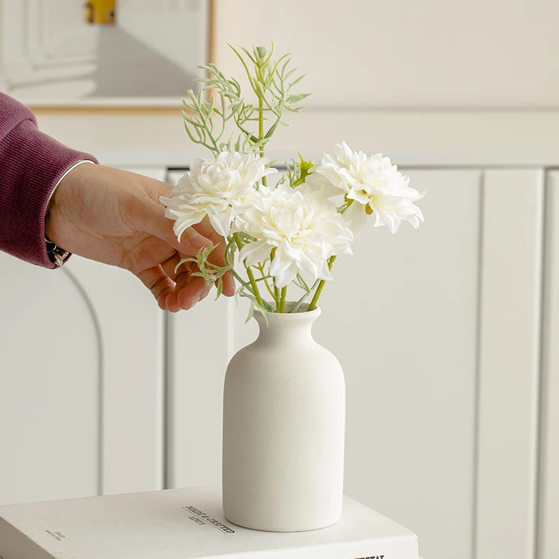 Elegant white artificial flowers in a modern vase held by a person, ideal for home decor