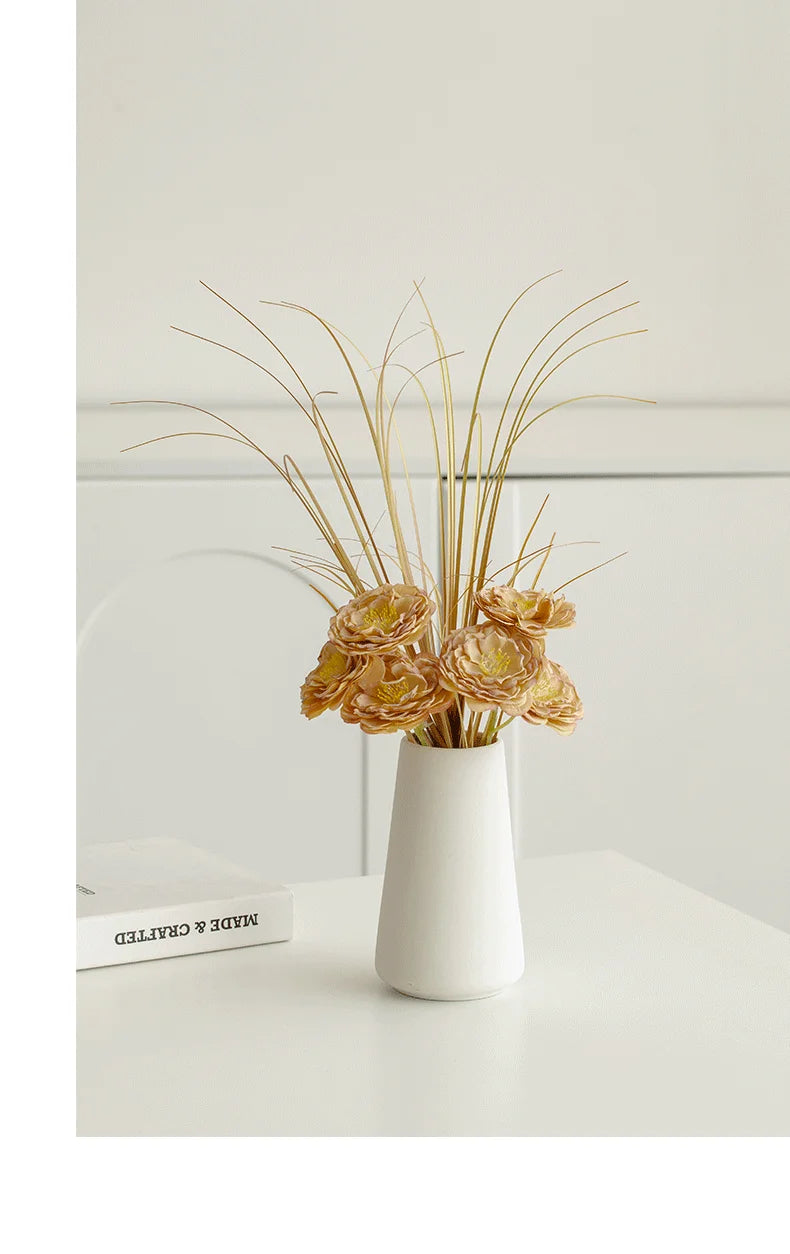 Elegant white vase with yellow decorative flowers and grass accents for home decor